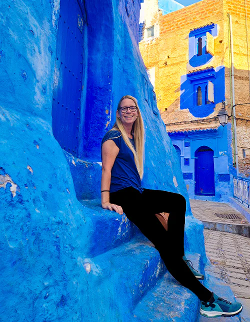 Kvinne sitter på en trapp i den blå byen Chefchaouen i Marokko