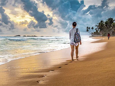 En kvinne går på stranden på Sri Lanka