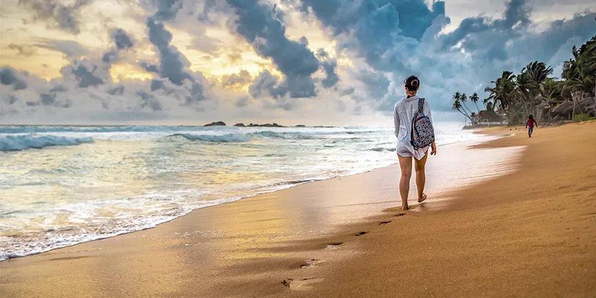 Kvinne går på stranden på Sri Lanka